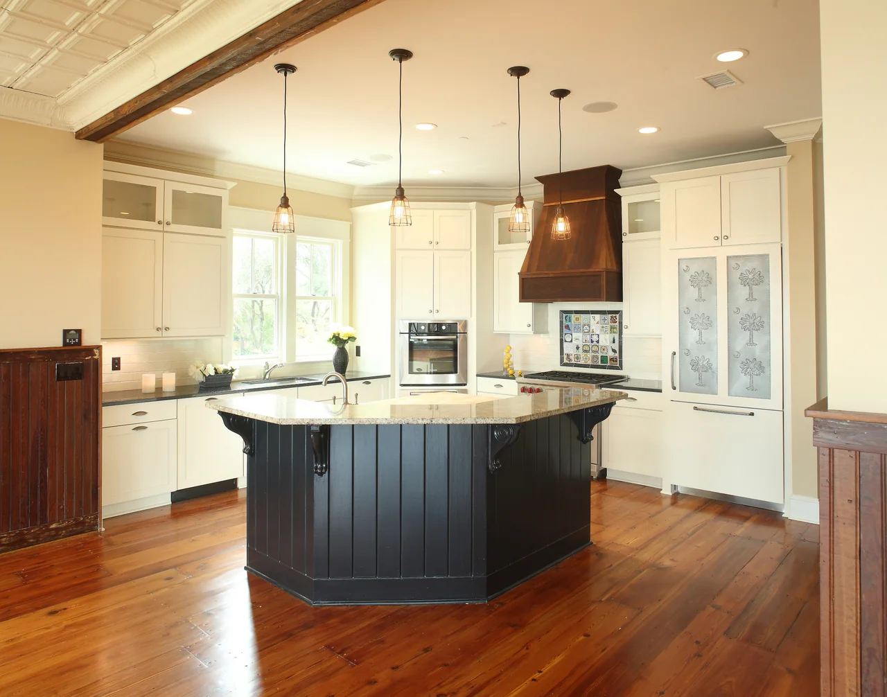 Kitchen with a dark island, light cabinets and wood floors