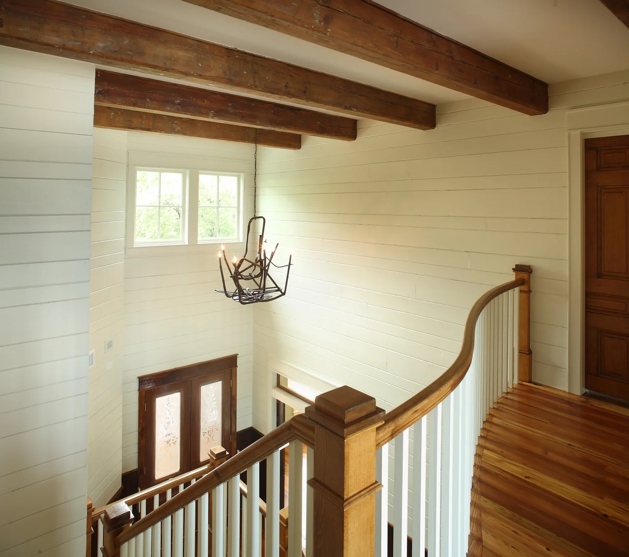 Stair landing with exposed beams and a pendant light